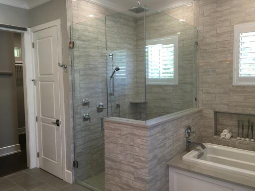 A bathroom with glass shower doors and white fixtures.