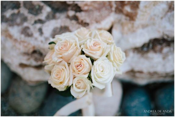 A bouquet with white roses on top of rocks.