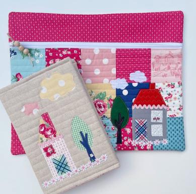 Two quilted pouches with houses and trees.