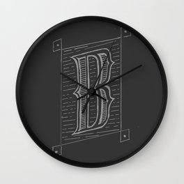The letter B is written in white on a black wall clock.