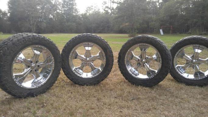 Four tires and two rims sitting on the grass.