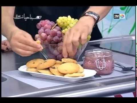 A person cutting grapes and cookies on a plate.